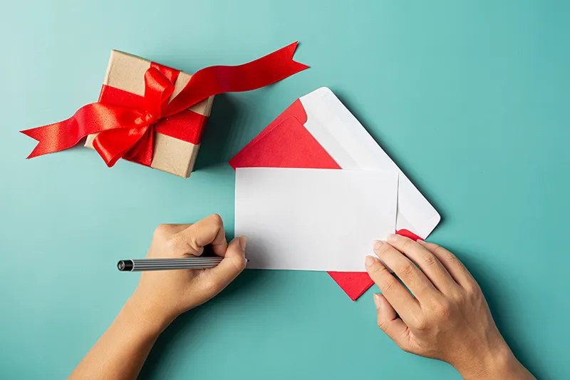 gift box put woman hand is writing greeting card
